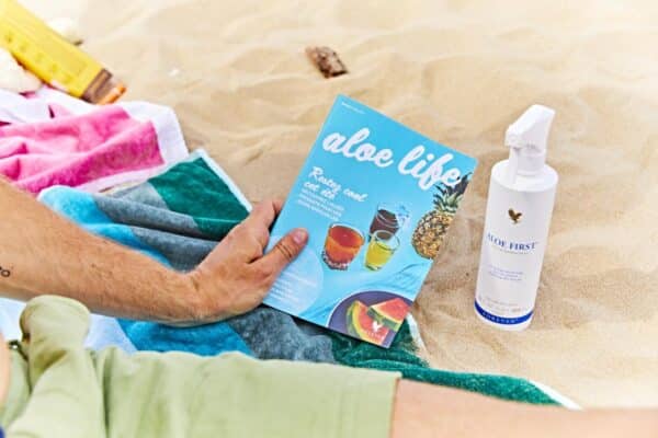 aloe first, poster cu produsul pe plaja langa brosura Aloe life